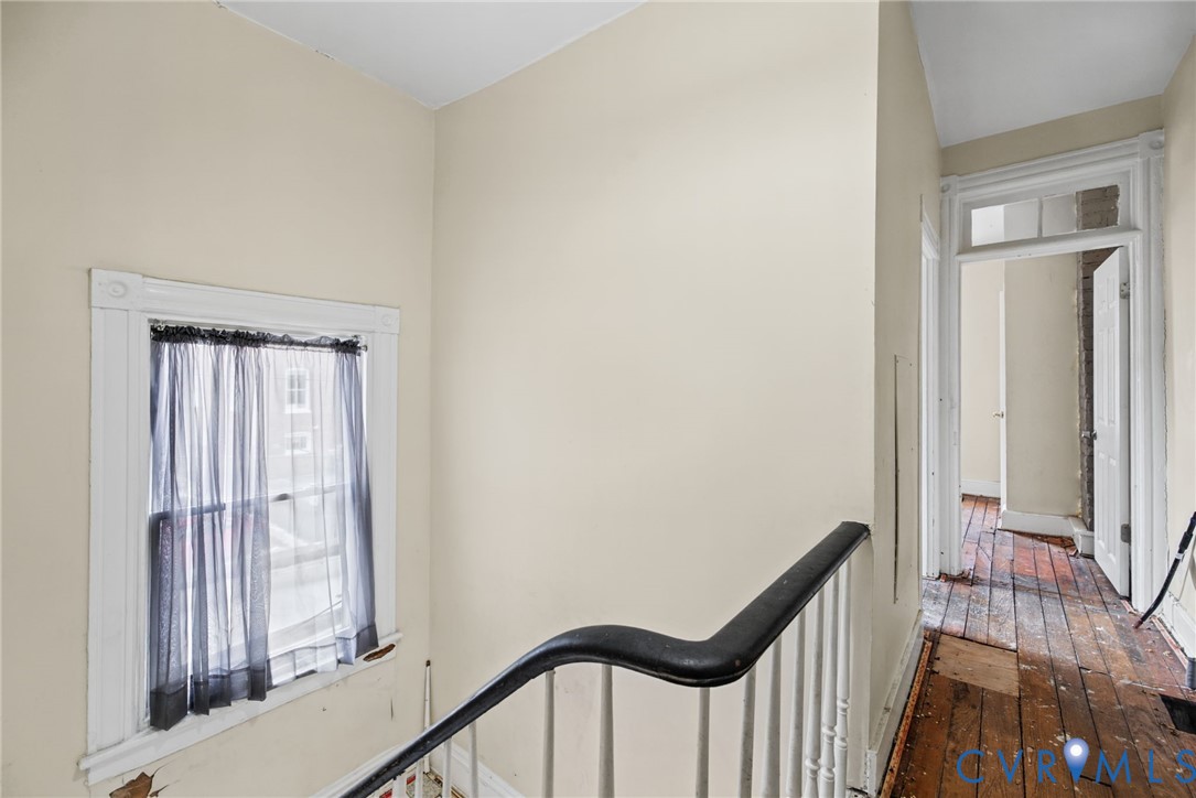Staircase featuring a painted wood handrail with balusters, wood-finish flooring, and window trim with a transomed door frame