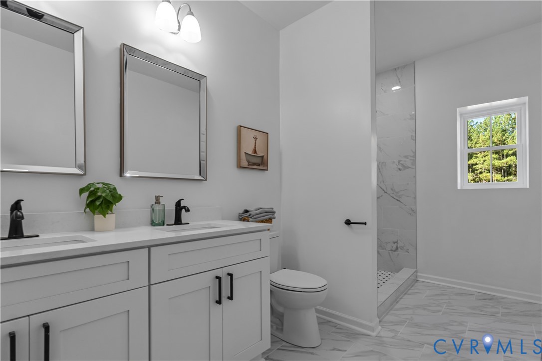 Double vanity featuring white cabinetry, quartz countertops, matte black fixtures, and rectangular mirrors, complemented by a walk-in shower with tile surround and stone-patterned floor tile