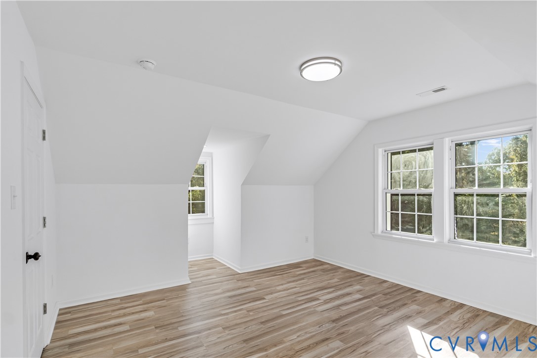 Interior space featuring neutral wall paint, wood-finish flooring, multi-pane windows, and a flush-mount circular light fixture