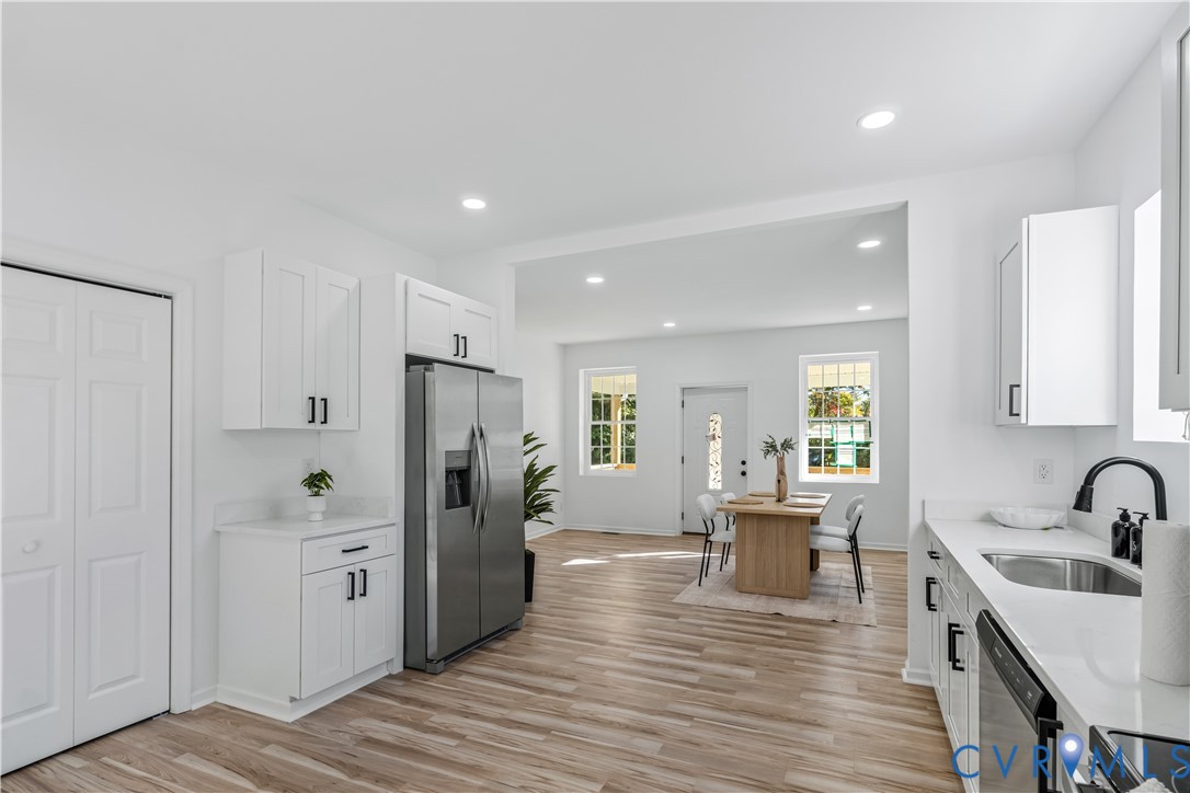 Kitchen featuring white cabinetry with matte black hardware, stone-finish countertops, stainless steel appliances, recessed lighting, and wood-finish flooring Kitchen featuring white cabinetry with matte black hardware, stone-finish countertops, stainless steel appliances, recessed lighting, and wood-finish flooring