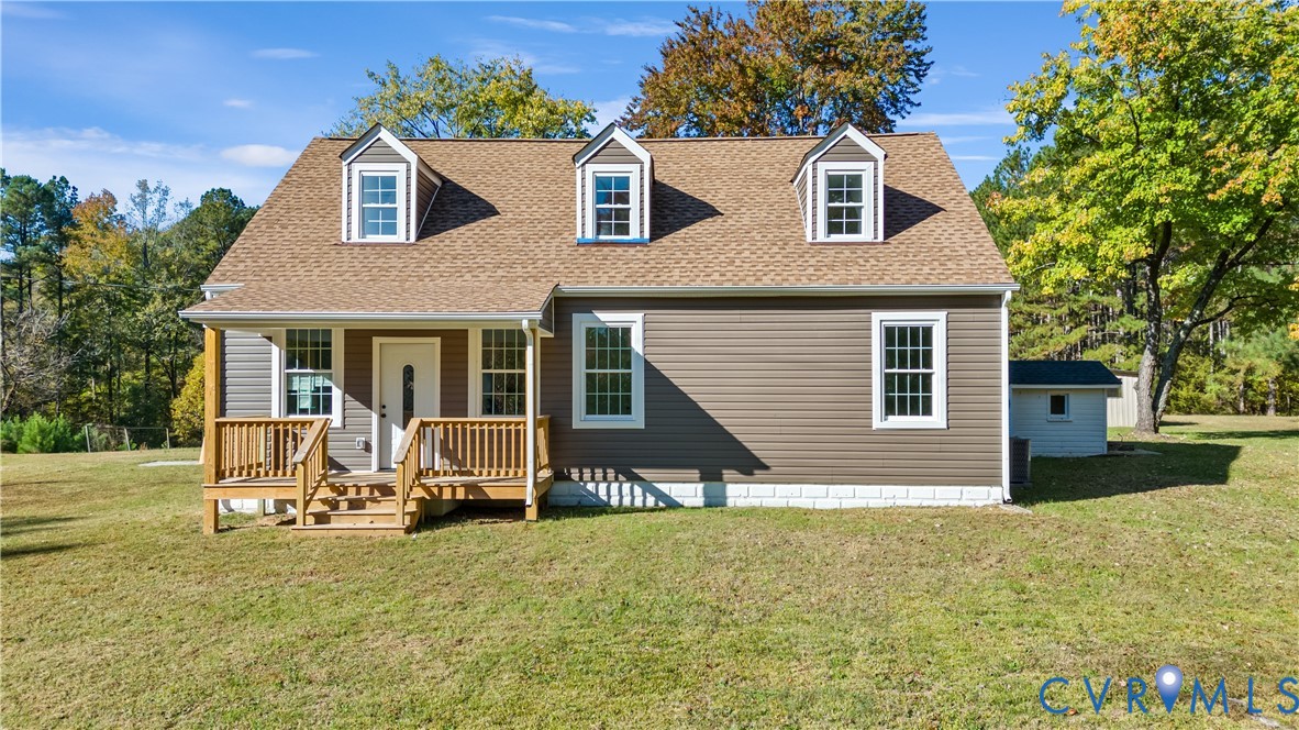 Cape Cod exterior featuring horizontal siding, a shingled roof, three dormer windows, and a raised wooden porch