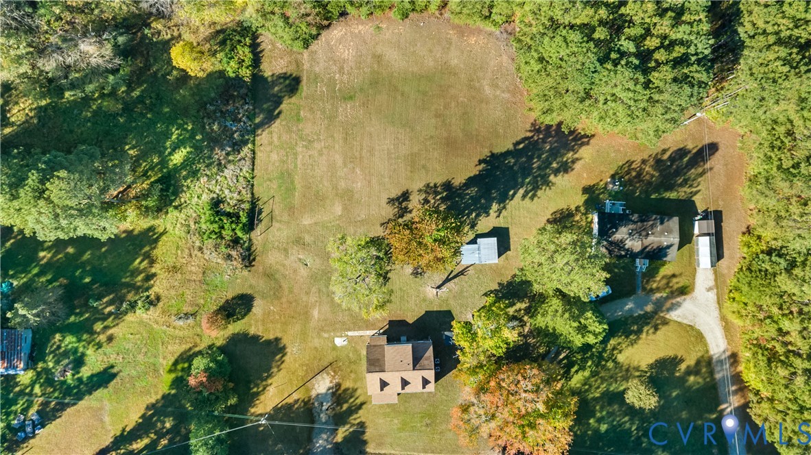 Expansive parcel featuring mature trees, open clearing, gravel driveway, and multiple structural improvements