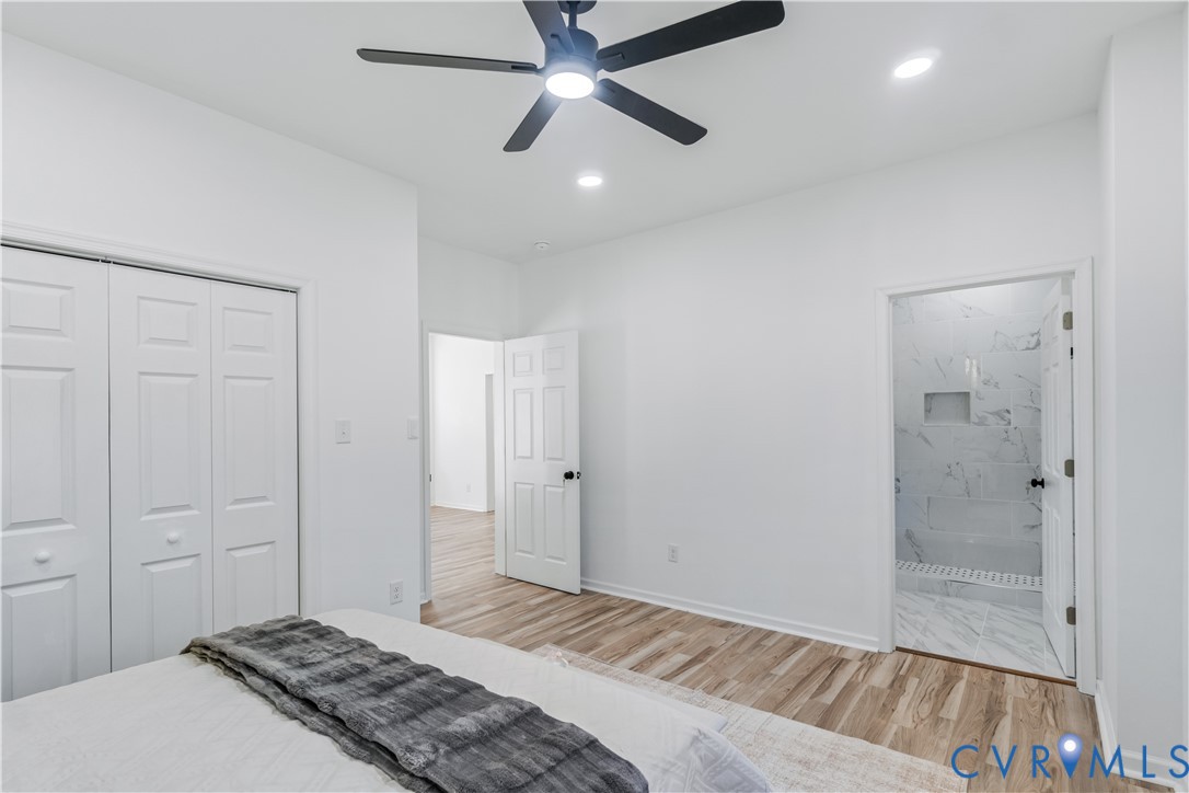 Neutral interior featuring wood-finish flooring, a matte black ceiling fan with integrated lighting, recessed lighting, and white six-panel doors