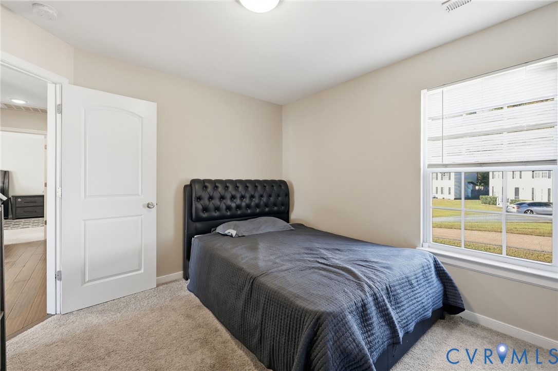 Neutral-toned interior featuring wall-to-wall carpeting, a multi-pane window with blinds, and a two-panel interior door