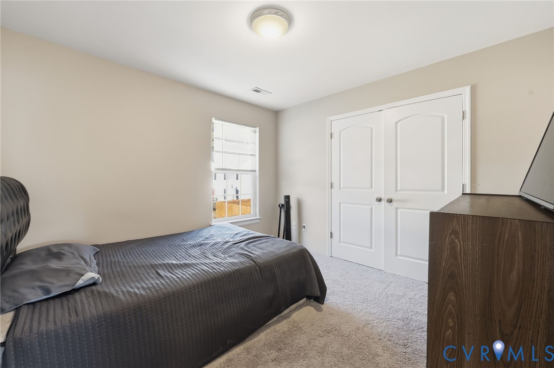 Neutral-toned interior featuring plush carpeting, dual-panel closet doors, single-hung window, and a flush-mount ceiling light