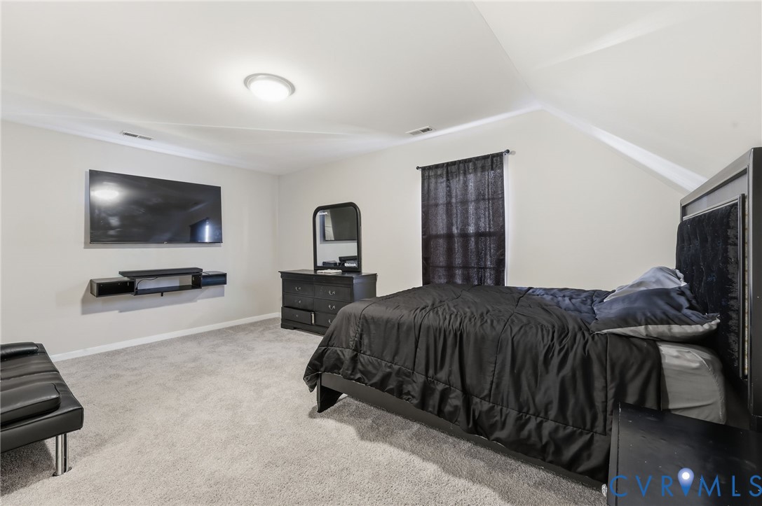 Neutral wall tones, wall-to-wall carpeting, and vaulted ceilings with a flush-mount light fixture