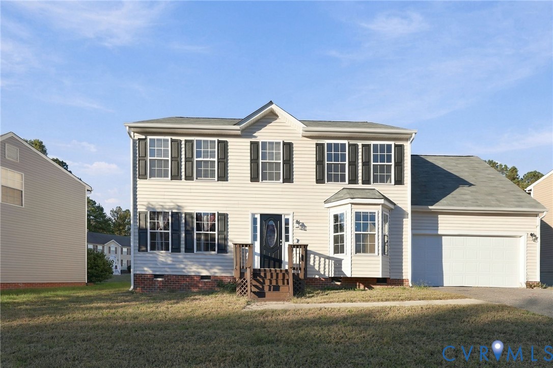 Two-story vinyl-sided exterior featuring dark shutters, a bay window, a brick foundation base, and an attached garage