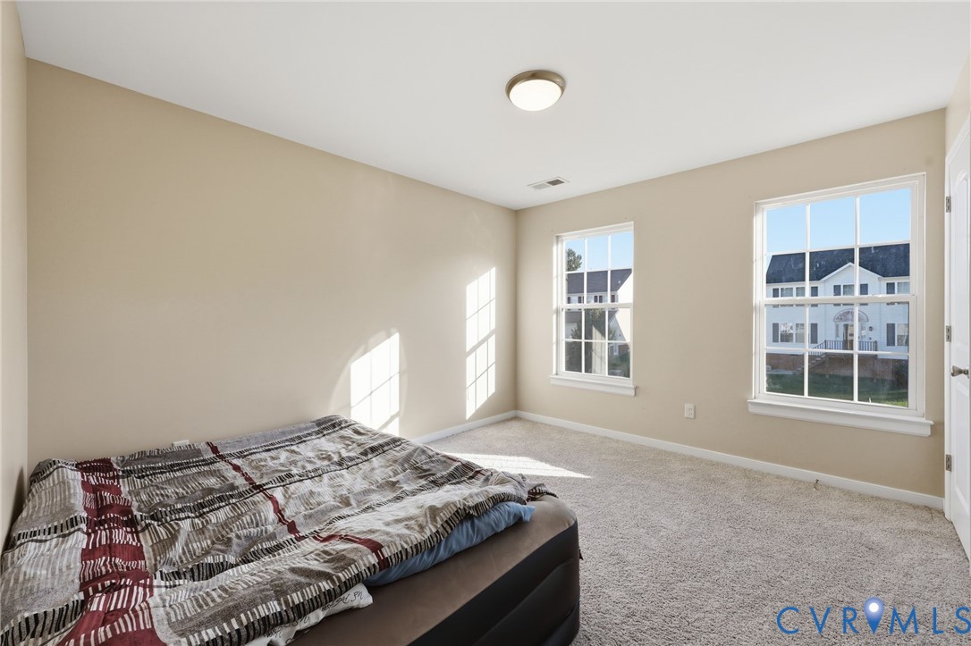 Interior space featuring neutral-tone walls, wall-to-wall carpeting, two double-hung windows with mullions, and a flush-mount ceiling light fixture