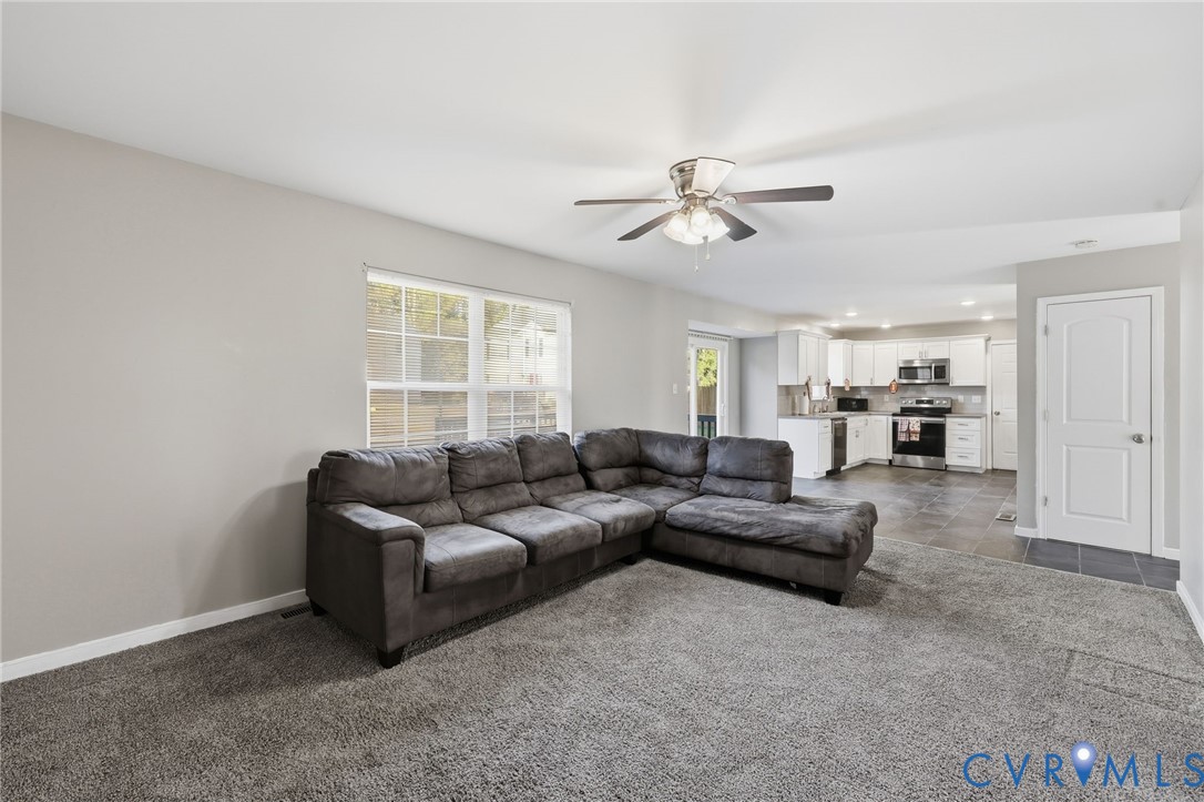 Neutral-toned interior featuring wall-to-wall carpeting, a multi-blade ceiling fan with integrated lighting, multi-pane window, and white interior doors