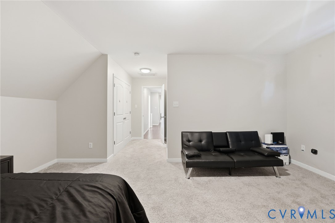 Neutral wall-to-wall carpeting, vaulted ceiling with architectural slope, and white-paneled interior doors