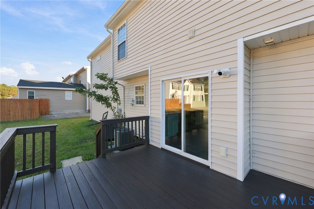Exterior deck with dark-stained wood-finish flooring and railing, light-toned horizontal siding, and sliding glass door