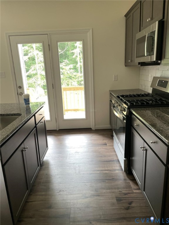 Kitchen featuring appliances with stainless steel finishes, backsplash, dark hardwood / wood-style flooring, and a healthy amount of sunlight