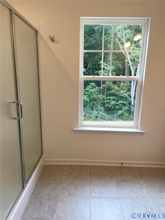 Bathroom featuring an enclosed shower, a healthy amount of sunlight, and tile patterned floors