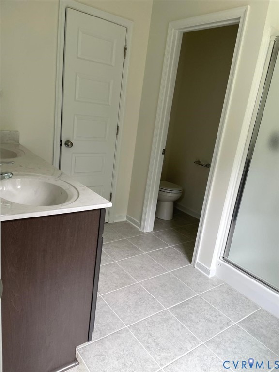 Bathroom featuring toilet, vanity, walk in shower, and tile patterned floors