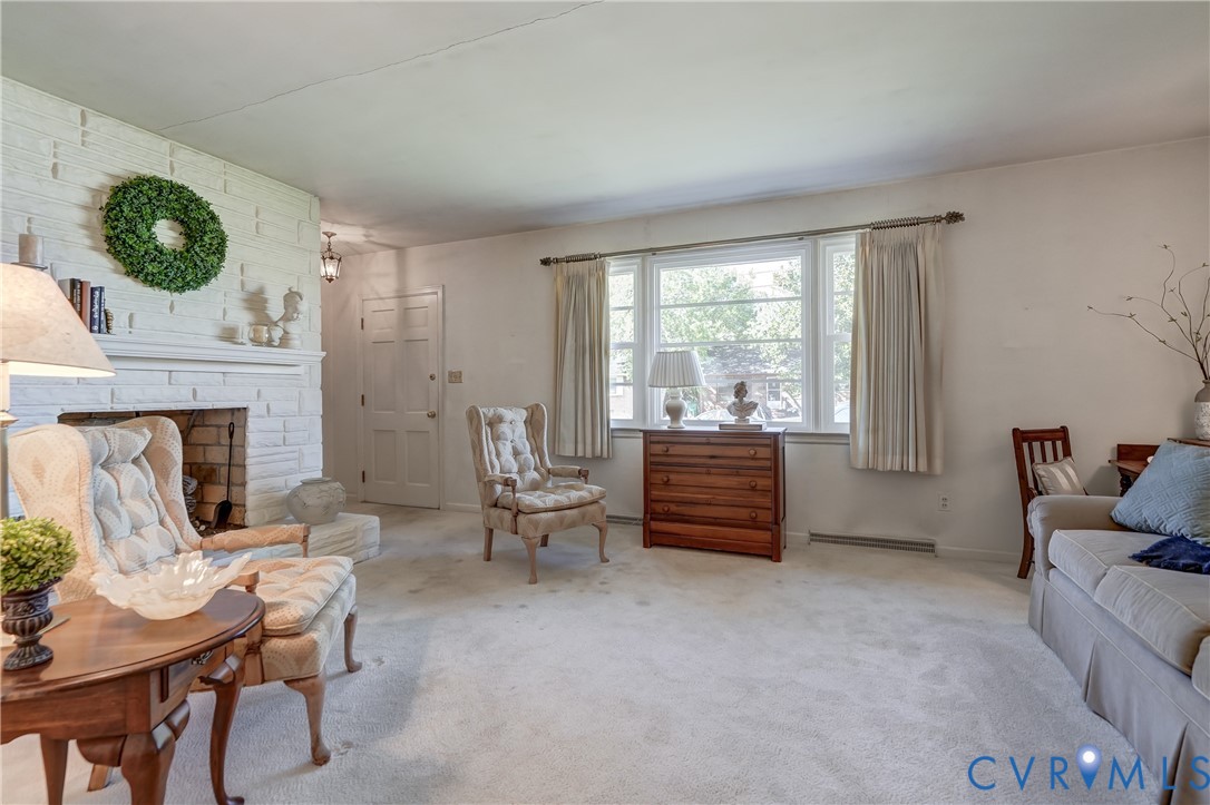Living area featuring a painted brick fireplace with a detailed mantel and a large window with natural light