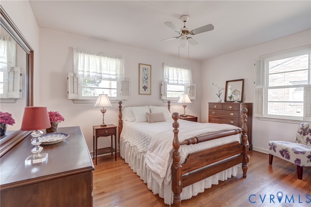 Hardwood flooring, triple-window configuration, ceiling fan with integrated lighting, and plantation-style interior shutters