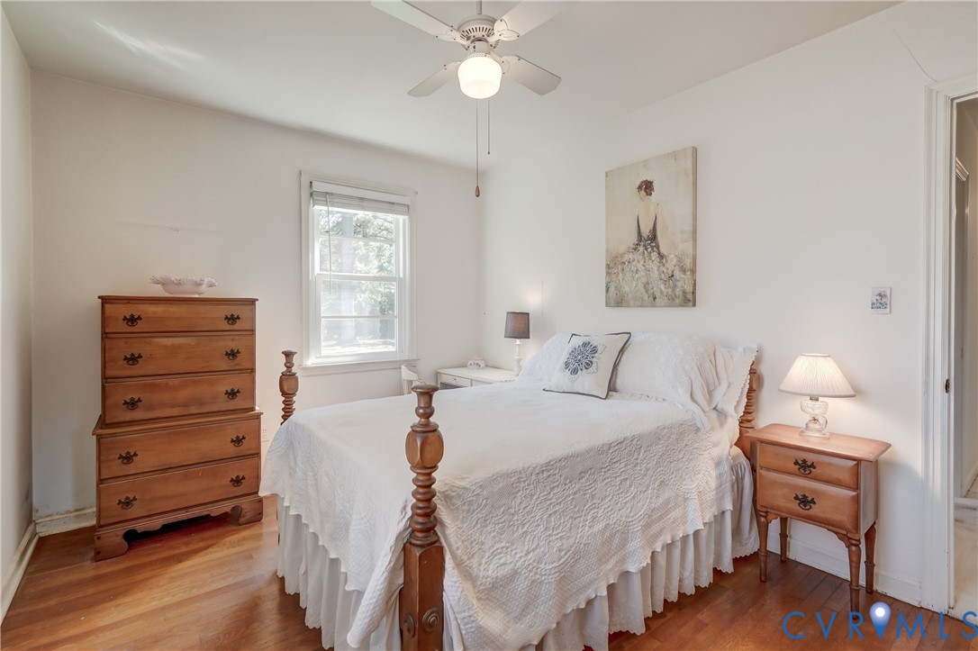 Wood-finish flooring, white walls, and a ceiling fan with integrated lighting