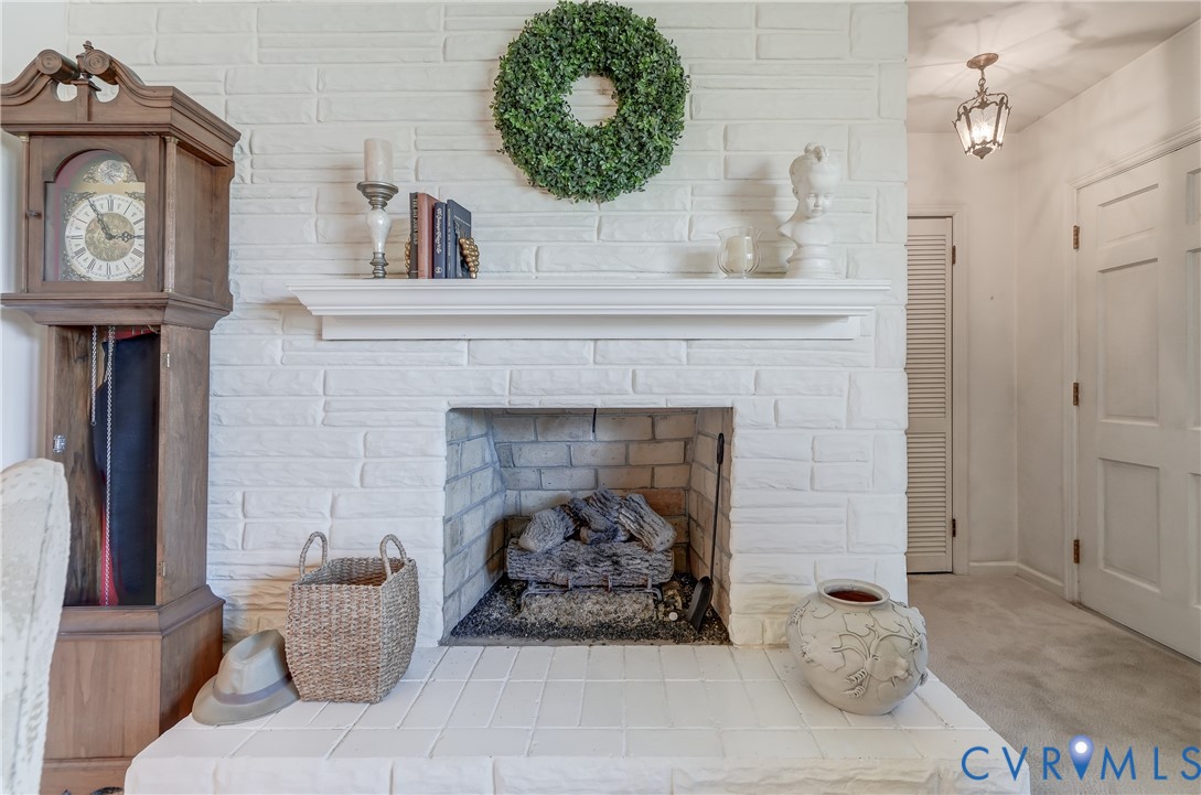 White painted brick fireplace featuring a classic mantel, a masonry hearth, and a pendant light fixture