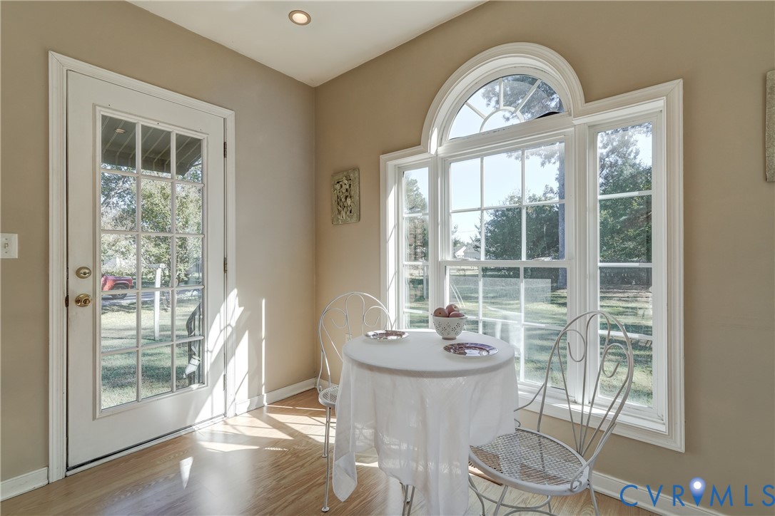Wood-finish flooring, multi-light glass door, and large arched window with grid detailing