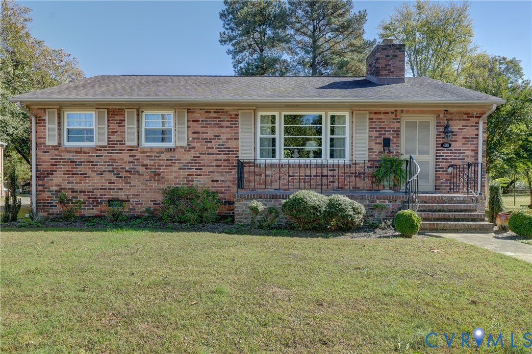 Ranch-style residence featuring a classic brick exterior, dimensional shingle roof, chimney, front porch with wrought-iron railing, and large multi-pane windows