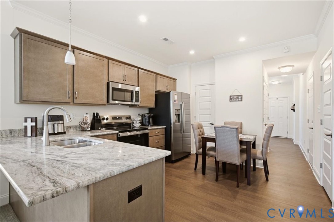 Kitchen featuring stone-finish countertops, stainless steel appliances, wood-finish cabinetry, recessed lighting, and wood-finish flooring