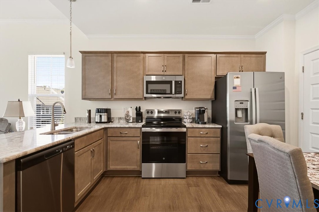 Kitchen featuring wood cabinetry, stone-finish countertops, stainless steel appliances, and wood-finish flooring