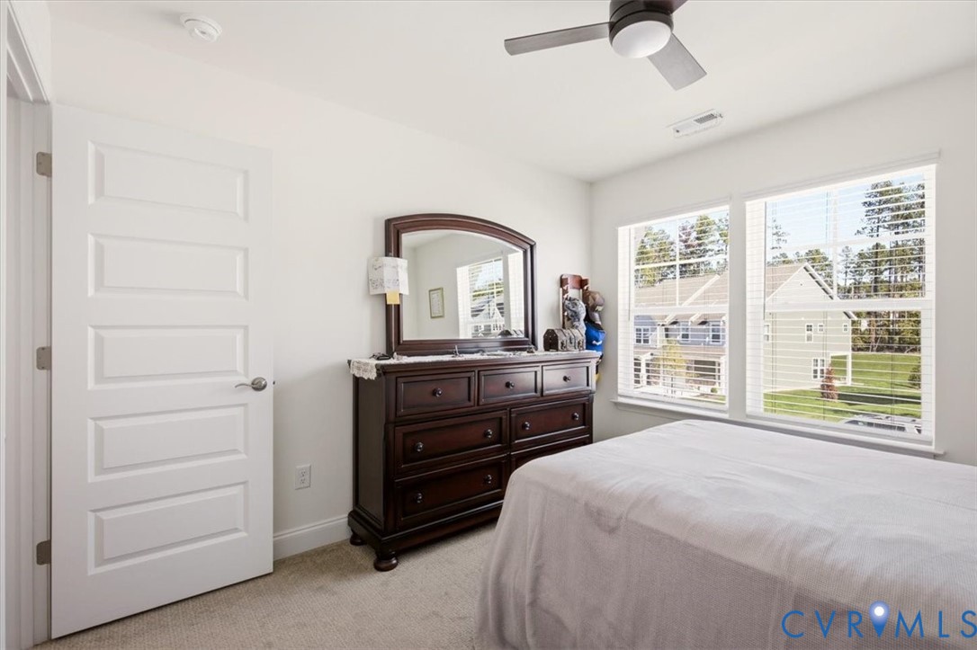 Neutral-toned carpeted flooring, multi-pane windows, and a ceiling-mounted light fixture with a multi-blade fan