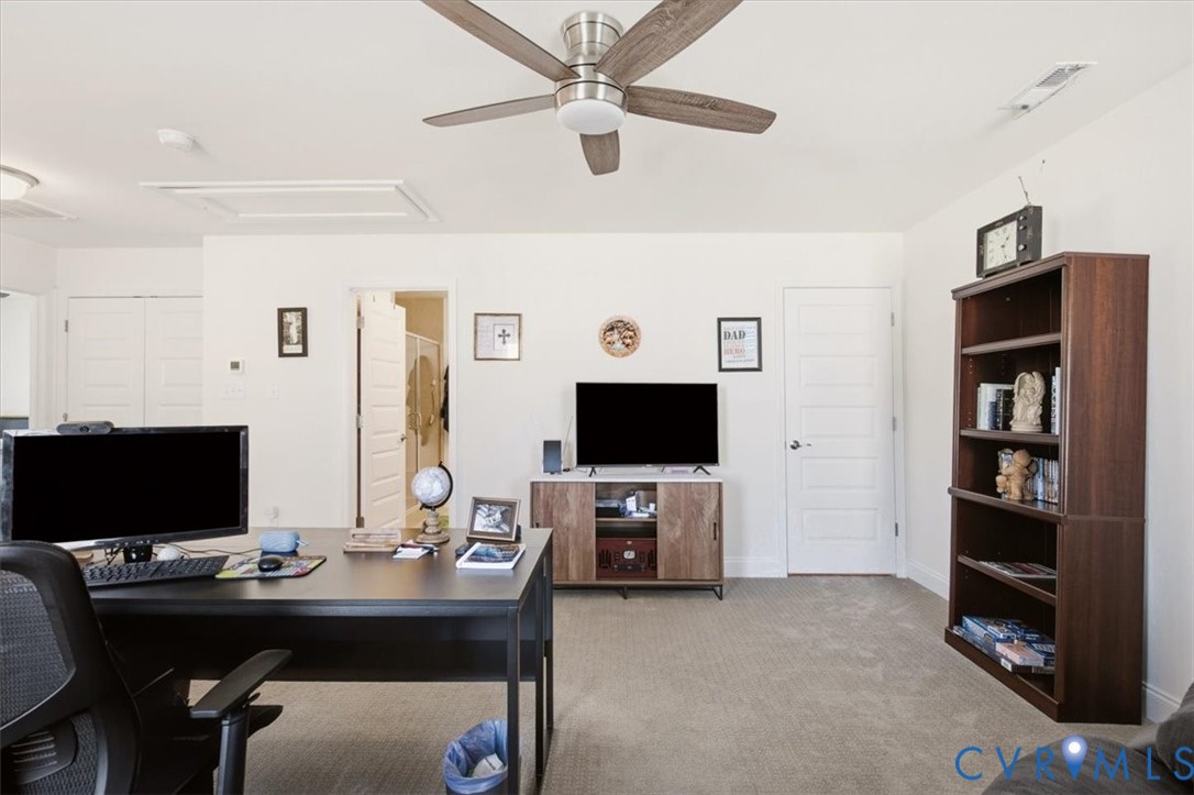 Neutral interior featuring a ceiling fan with integrated lighting, carpeted flooring, and multiple interior paneled doors