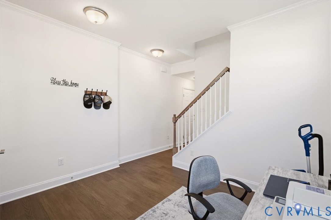 Wood-finish flooring, crown molding, and a staircase with a wooden handrail and white balusters