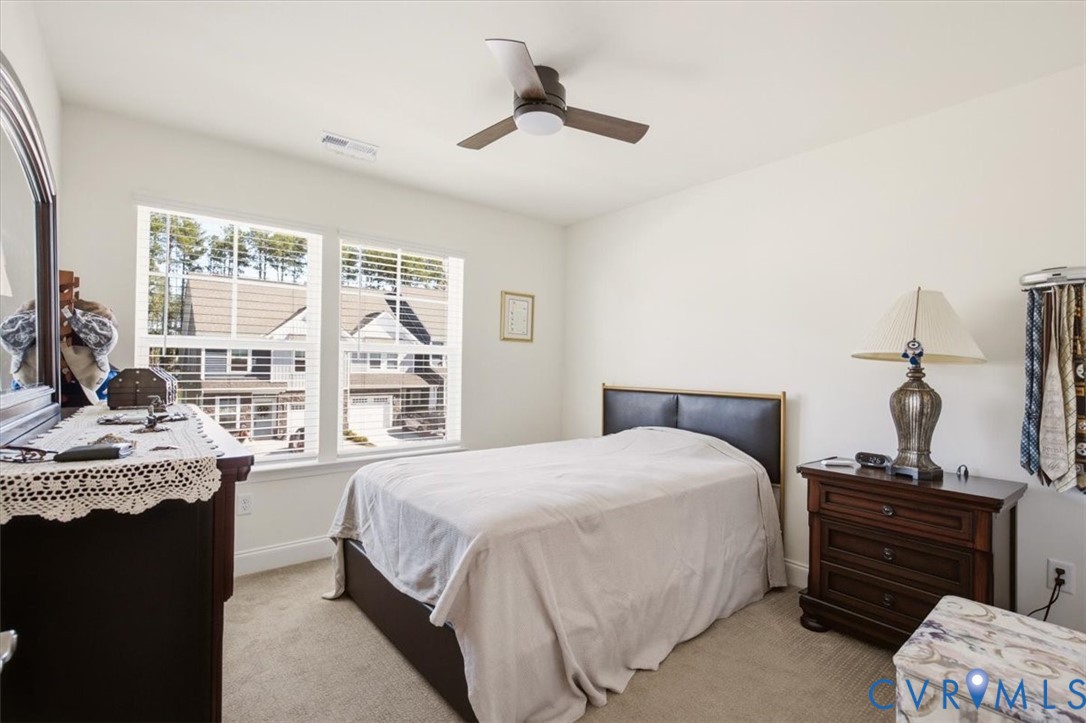 Neutral-toned carpeted flooring, dual-pane windows with horizontal blinds, and a three-blade ceiling fan with integrated lighting