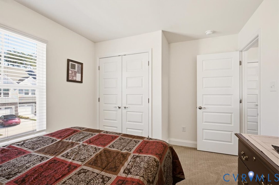 Neutral-toned room featuring wall-to-wall carpeting, a multi-pane window, and two paneled interior doors, including a double-door closet