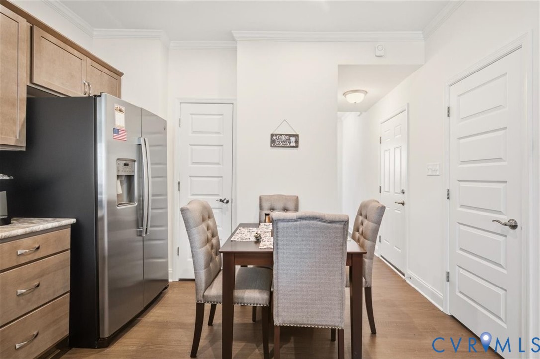 Kitchen featuring wood-finish cabinetry, stainless steel side-by-side refrigerator, wood-finish flooring, and crown molding