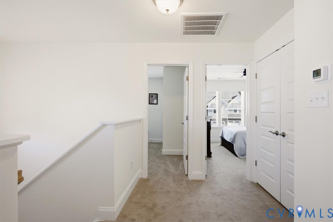Hallway featuring neutral carpet flooring, white paneled interior doors, and overhead flush-mount lighting