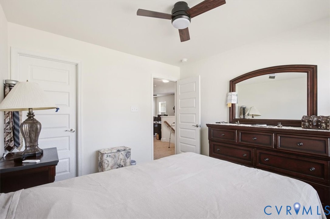 Neutral-toned bedroom featuring three-panel interior doors, a central ceiling fan with integrated lighting, and carpeted flooring