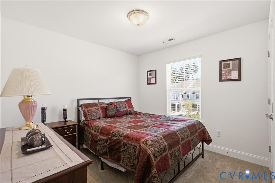Neutral-toned wall-to-wall carpeting, single-pane window with natural light, and a flush-mount ceiling light fixture