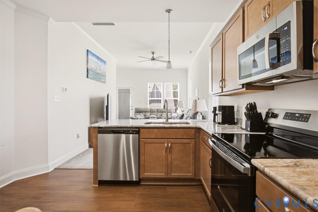 Kitchen featuring wood cabinetry, stone-finish countertops, stainless steel appliances, and wood-finish flooring