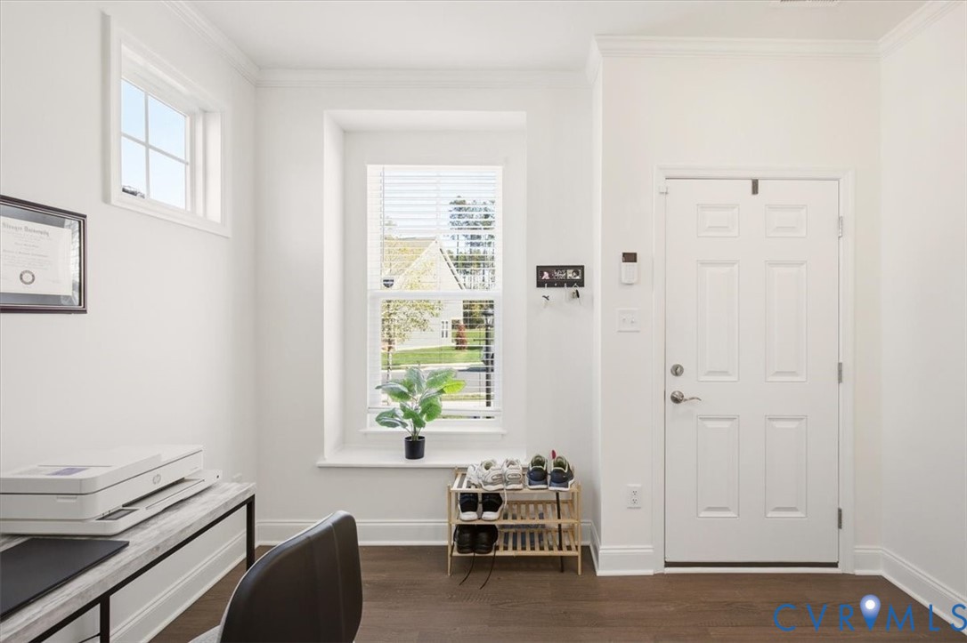 Entry featuring wood-finish flooring, a six-panel door, crown molding, and two windows with a deep sill
