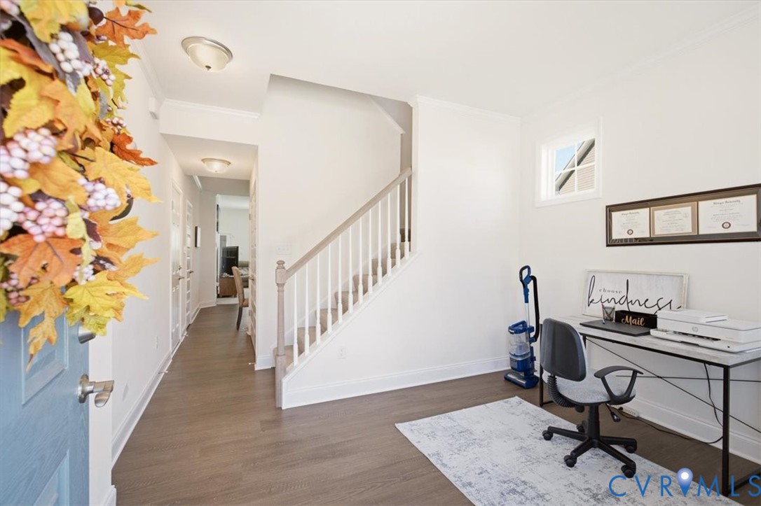 Foyer featuring wood-finish flooring, staircase with a white balustrade and neutral-toned handrail, and recessed lighting