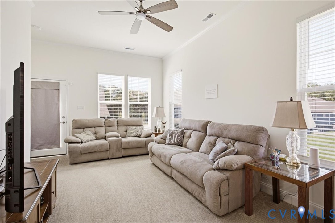 High ceilings, neutral wall color, multiple large windows, and a ceiling fan with integrated lighting