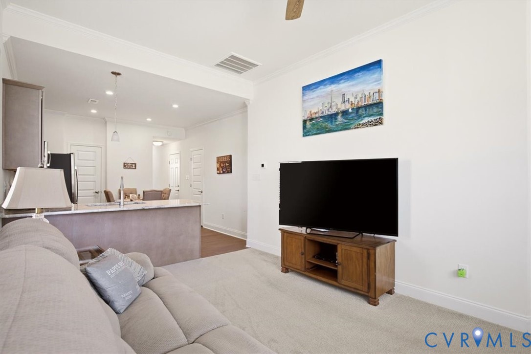 Open-concept interior featuring recessed lighting, ceiling fan, carpeted flooring, and a kitchen peninsula with stone-finish countertop