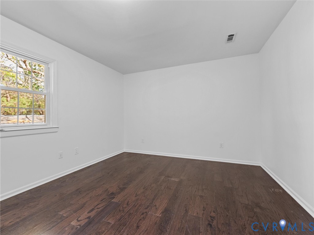Neutral-toned interior room featuring wood-finish flooring and a multi-pane window with a white frame