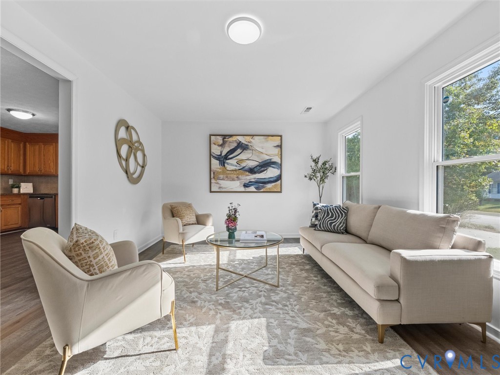 Living area featuring wood-finish flooring, neutral walls, large windows, and a ceiling-mounted light fixture