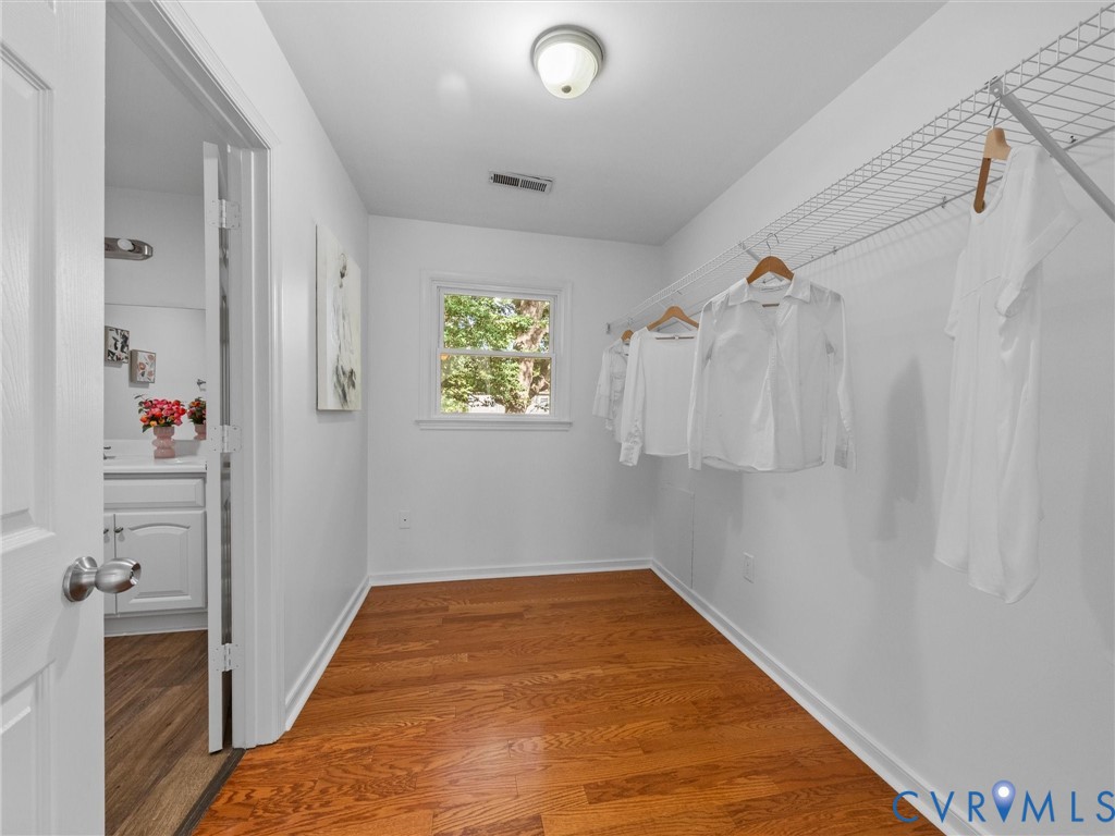 Walk-in closet featuring wood-finish flooring, a white-framed window, and wire shelving