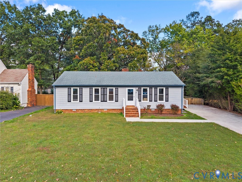 Ranch-style exterior featuring light-toned horizontal siding, decorative window shutters, a brick foundation, and a concrete driveway Ranch-style exterior featuring light-toned horizontal siding, decorative window shutters, a brick foundation, and a concrete driveway