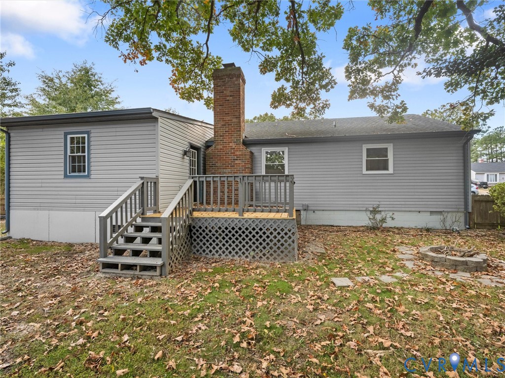 Exterior siding, central masonry chimney, raised wooden deck with lattice skirting, and stone fire pit