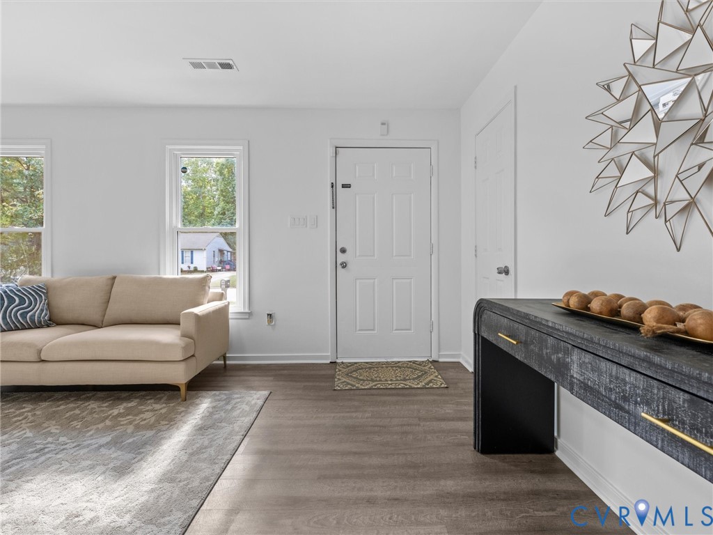 Neutral interior space featuring wood-finish flooring, white walls, and multiple double-hung windows