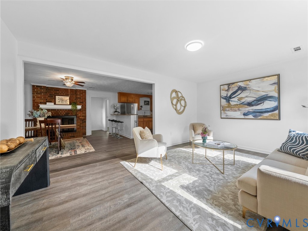 Living area featuring wood-finish flooring and a floor-to-ceiling brick fireplace with a custom mantle