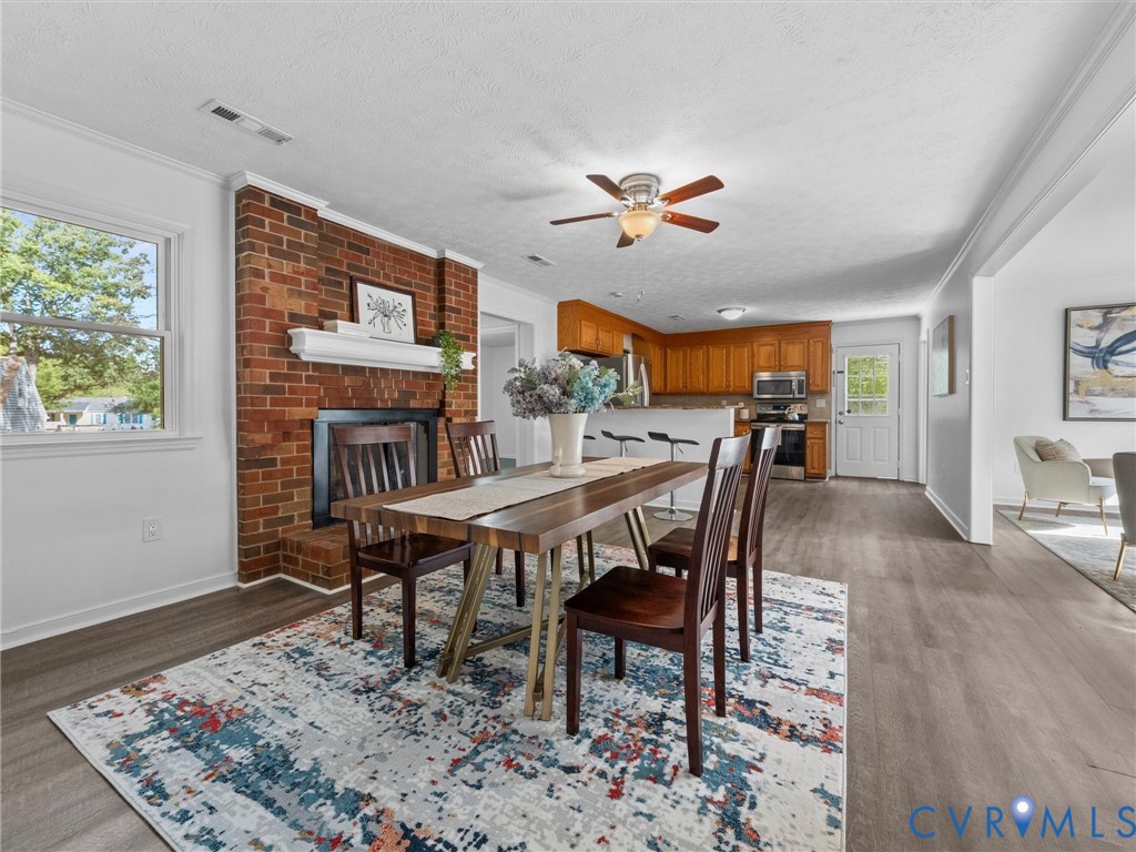 Exposed brick fireplace with a decorative mantel, wood-finish flooring, and recessed ceiling lighting
