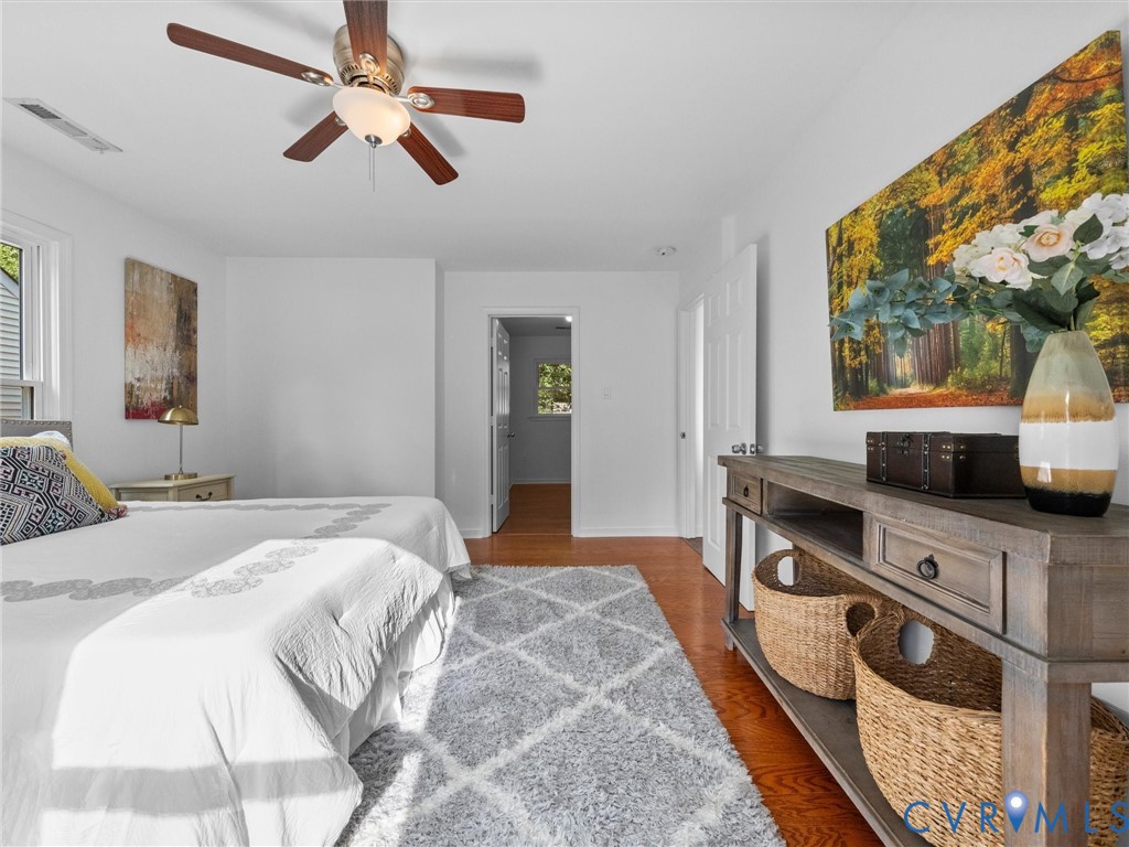 Wood-finish flooring, central ceiling fan with integrated lighting, and white six-panel interior doors