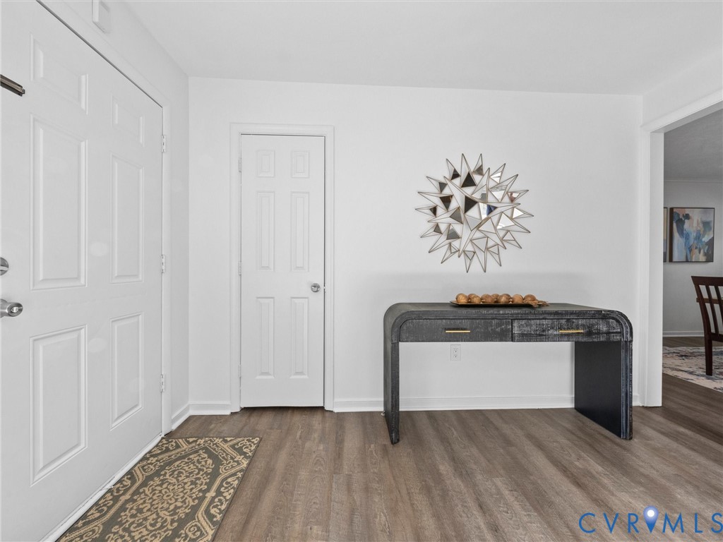 Entrance featuring a six-panel door, wood-finish flooring, and crisp neutral wall paint